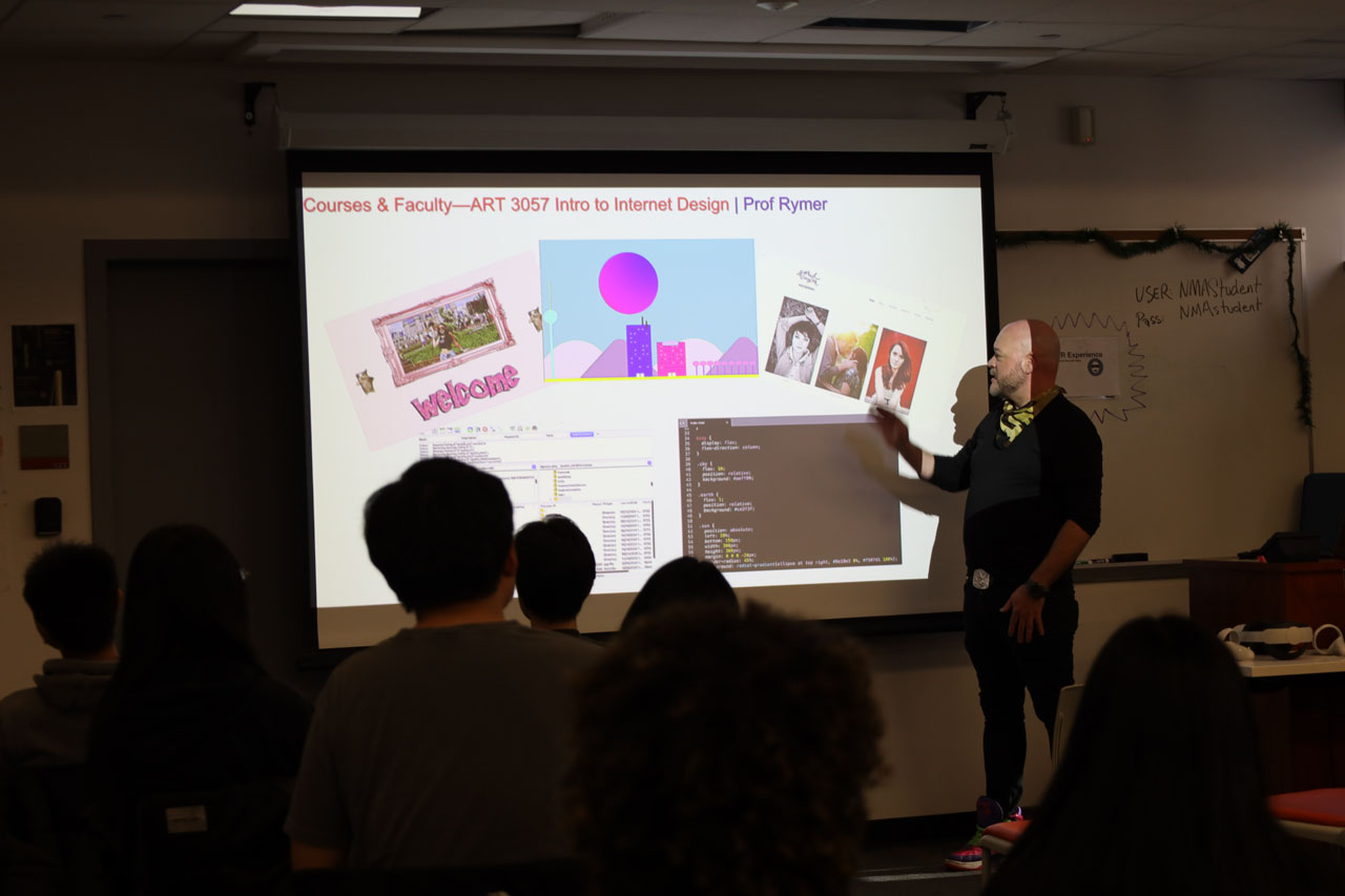 Nick Rymer presenting about the Intro to Internet Design course. Examples of student websites are on the screen behind him.
