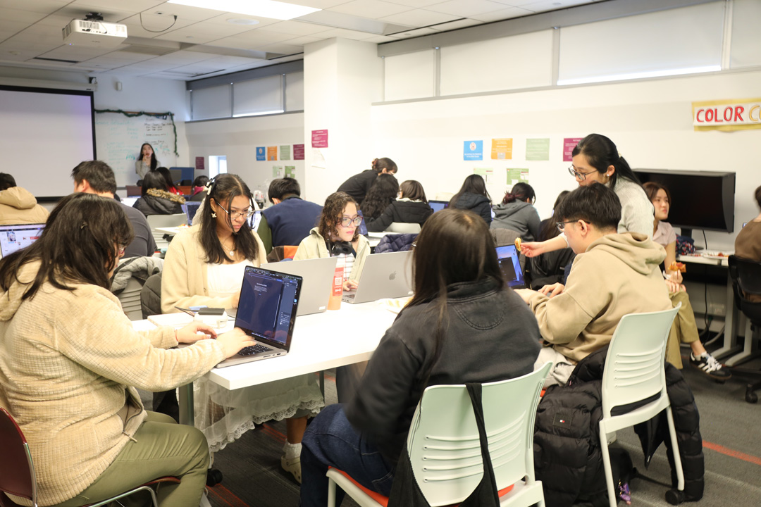 Students working around a rectangular table, using laptops.