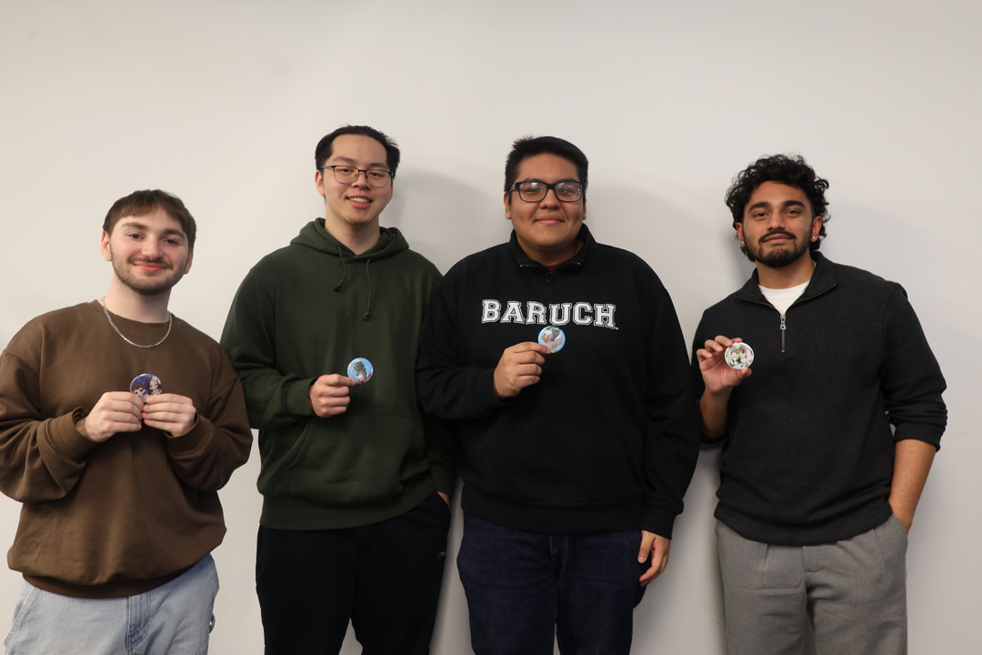 Four smiling students standing in a row posing with their handmade buttons.