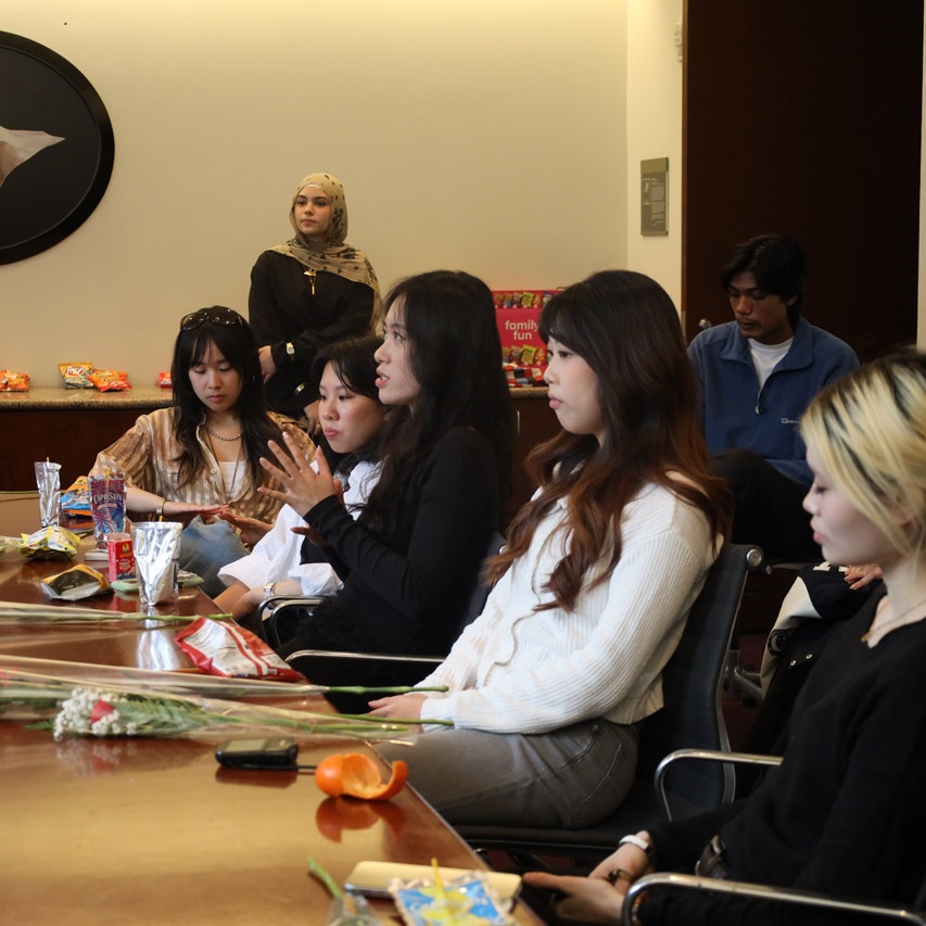 People sit around a table with flowers.