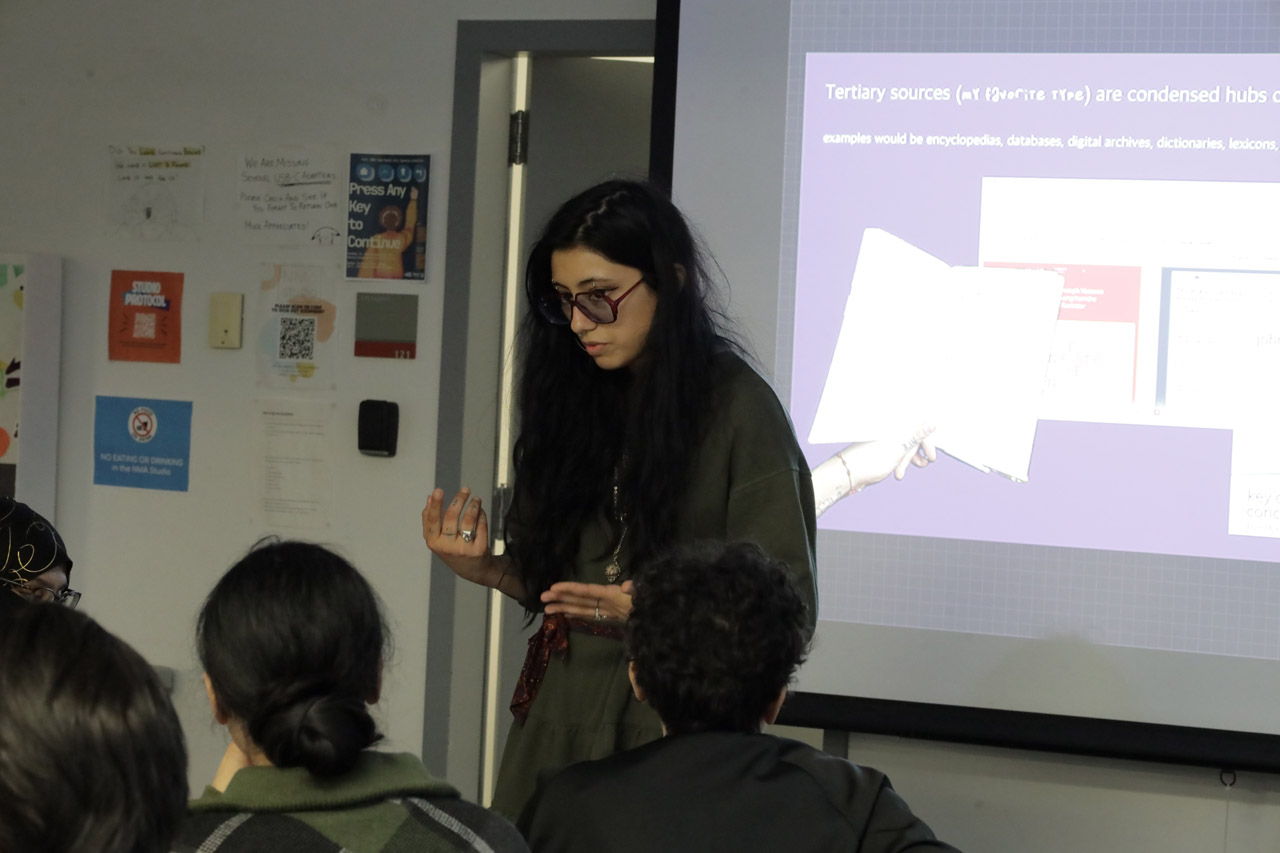 A woman with long black hair presents about tertiary sources.